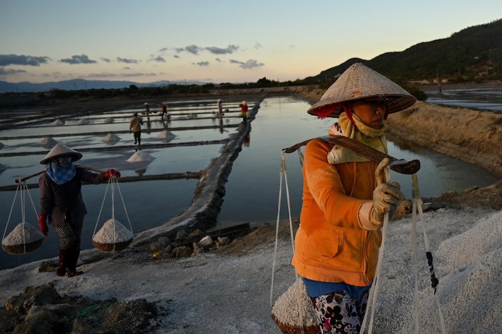 Workers carry harvested salt in bamboo baskets in southern Vietnam’s Hon Khoi salt fields April 22, 2019. — AFP pic
