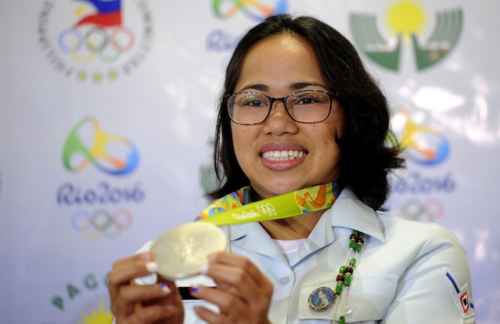 Philippines silver medallist at the Rio Olympics, Hidilyn Diaz, shows her medal during a press conference as she arrives at the Manila International Airport in Manila August 11, 2016. u00e2u20acu201d AFP pic