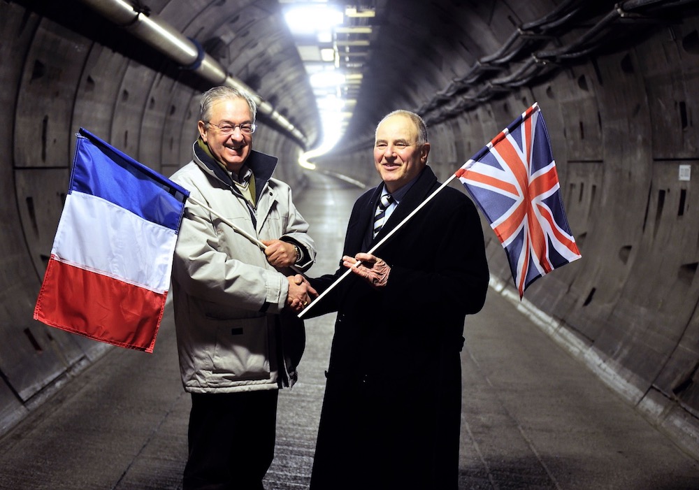 In this file photograph taken on February 10, 2014, former workers France's Philippe Cozette (left) and Britain's Graham Fagg, hold their national flags as they shake hands near Coquelles, 20 years after the event. — AFP
