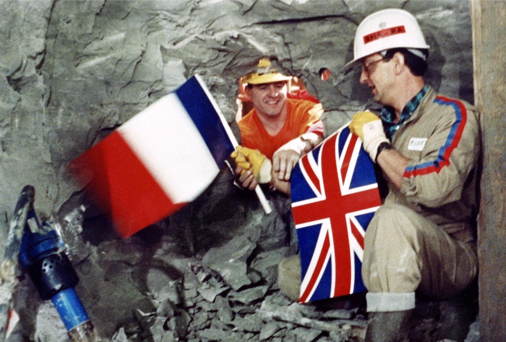 In this file photograph taken on December 1, 1990, Tunnel workers Philippe Cozette from France and Graham Fagg from England shake hands while holding national flags, during the historic breakthrough in the Channel Tunnel. u00e2u20acu201d AFP pic