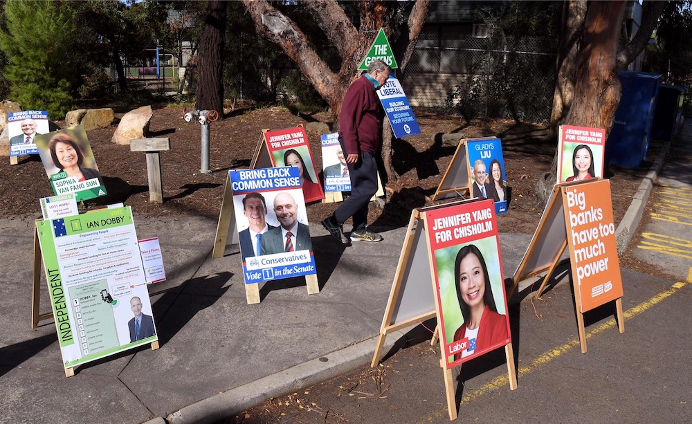A photograph taken in Melbourne on May 7, 2019, shows a pre-poll voter walking through the candidate's placards after voting in the May 18 election for the outer Melbourne electorate of Chisholm. u00e2u20acu201d AFP pic