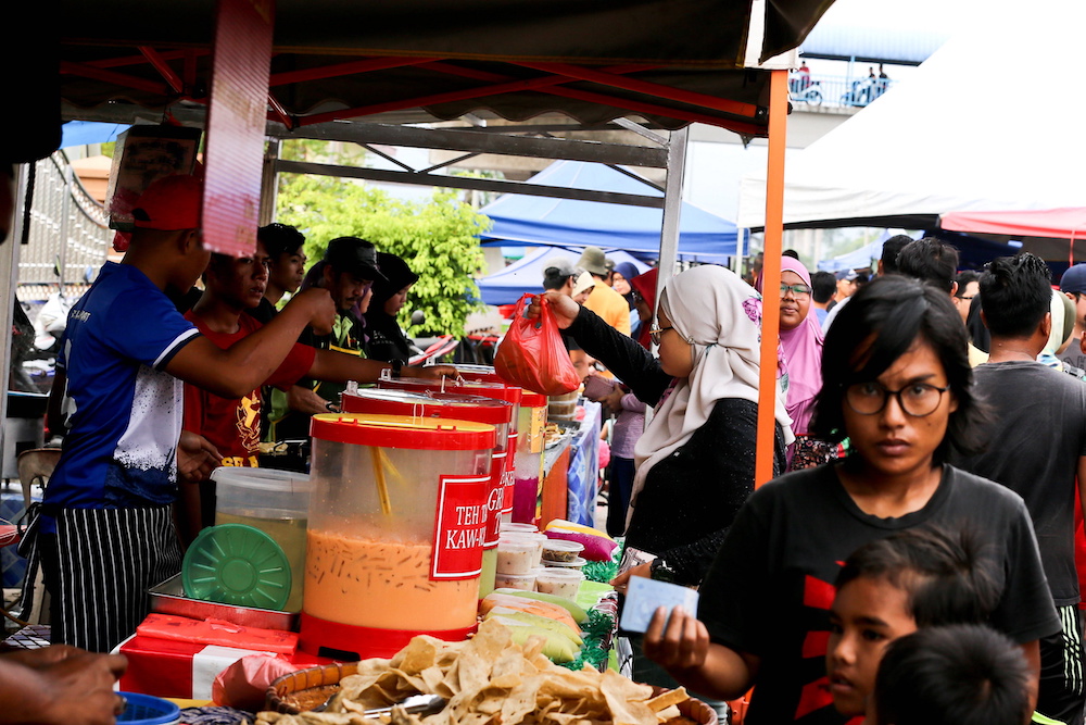 A customer buys a drink packed in single-use plastic at a Ramadan bazaar in Kampung Kanchong Darat. — Picture by Sayuti Zainudin