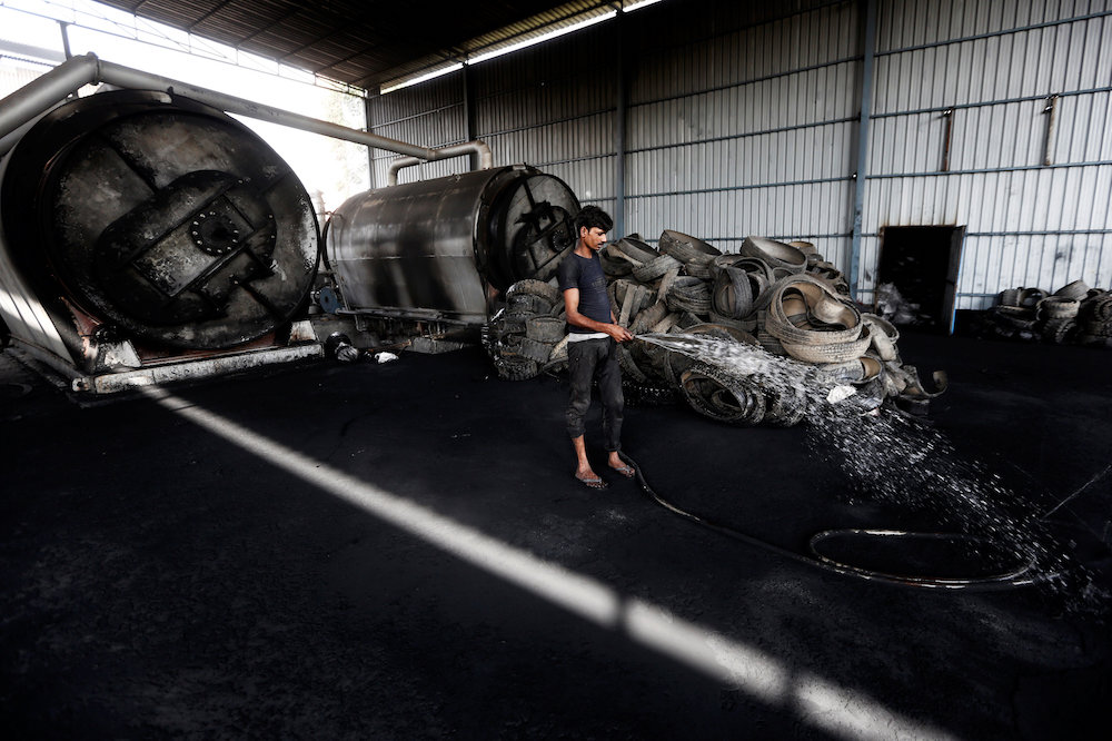A labourer sprays water around a reactor at a pyrolysis unit in Jokhabad industrial area in the northern state of Uttar Pradesh, India May 9, 2019. — Reuters pic