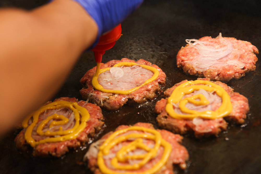 What drives up the deliciousness of the Gojira: Mustard and onions placed on top of the smashed beef patties that is pan fried further.