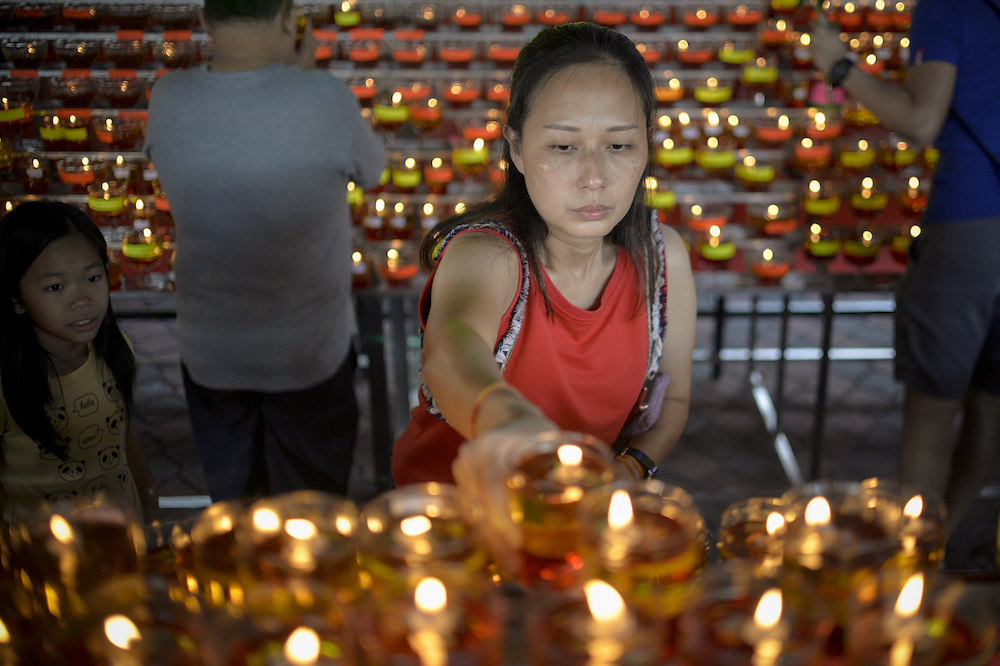 A Buddhist devotee lights an oil lamp to mark Wesak Day at the Thai Buddhist Chetawan Temple in Petaling Jaya May 19, 2019. u00e2u20acu201d Picture by Mukhriz Hazim