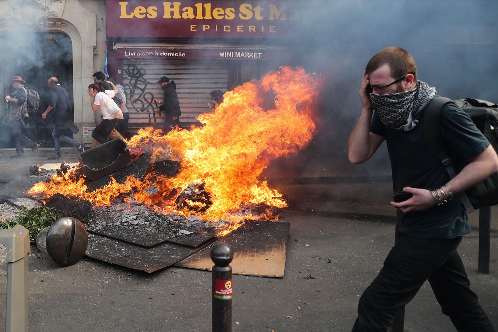 A man reacts as he walks past a fire erupted in the street during clashes with police on the sidelines of the annual May Day rally in Paris May 1, 2019. u00e2u20acu201d AFP pic