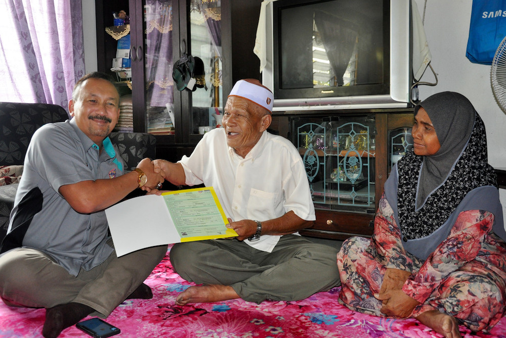 National Registration Department (NRD) director-general Datuk Ruslin Jusoh presents Embong Muhamad with his new birth certificate and MuyKad at his home in Kampung Lay Out Gerai, Jertih May 4, 2019. u00e2u20acu201d Bernama pic
