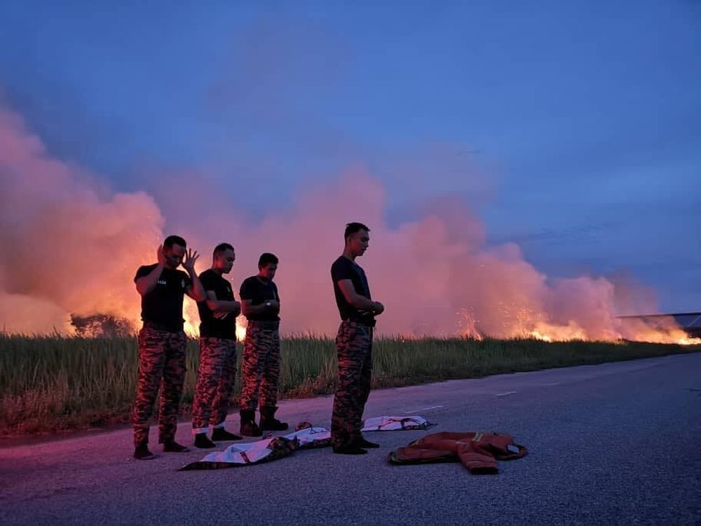 A group of Fire & Rescue Department personnel perform prayers on the roadside after being called into duty during u00e2u20acu02dciftaru00e2u20acu2122. u00e2u20acu201d Picture via Facebook/ Friends of Bomba Malaysia