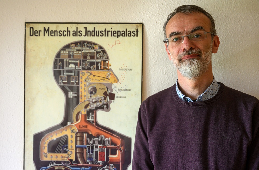 Department head at the Institute of Anatomy of the Brandenburg Medical School Andreas Winkelmann poses next to a poster from 1926 detailing the human body as an Industry Palace, in his office in Neuruppin on April 30, 2019. u00e2u20acu201d AFP pic     