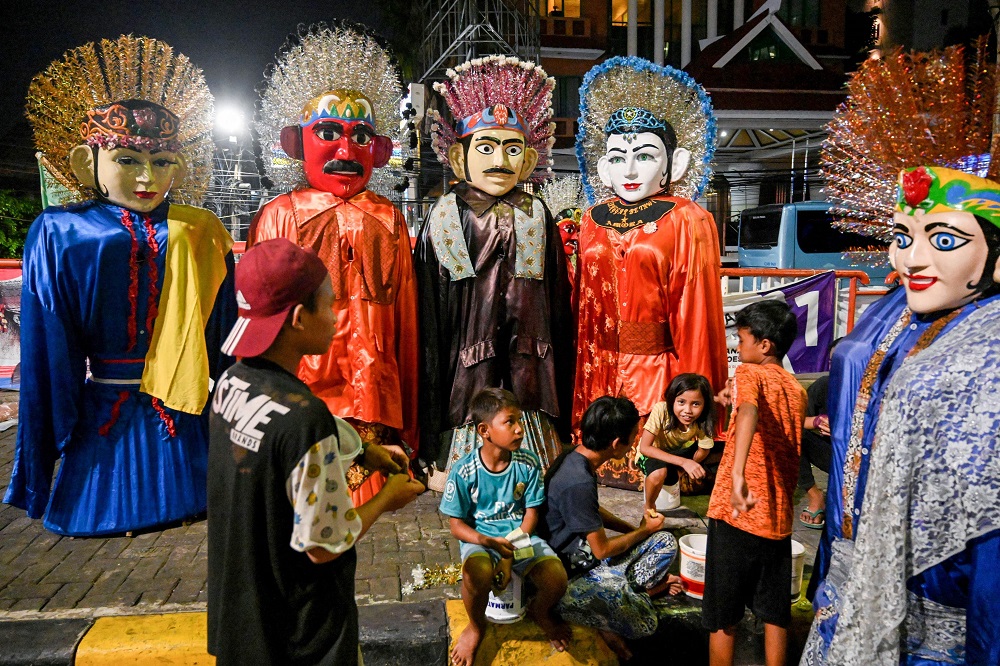 This picture taken on April 10, 2019 shows children taking a break from make a living by strapping on two-metre brightly coloured folk effigies known as Ondel-ondel and busking on the streets of Jakarta. u00e2u20acu201d AFP pic