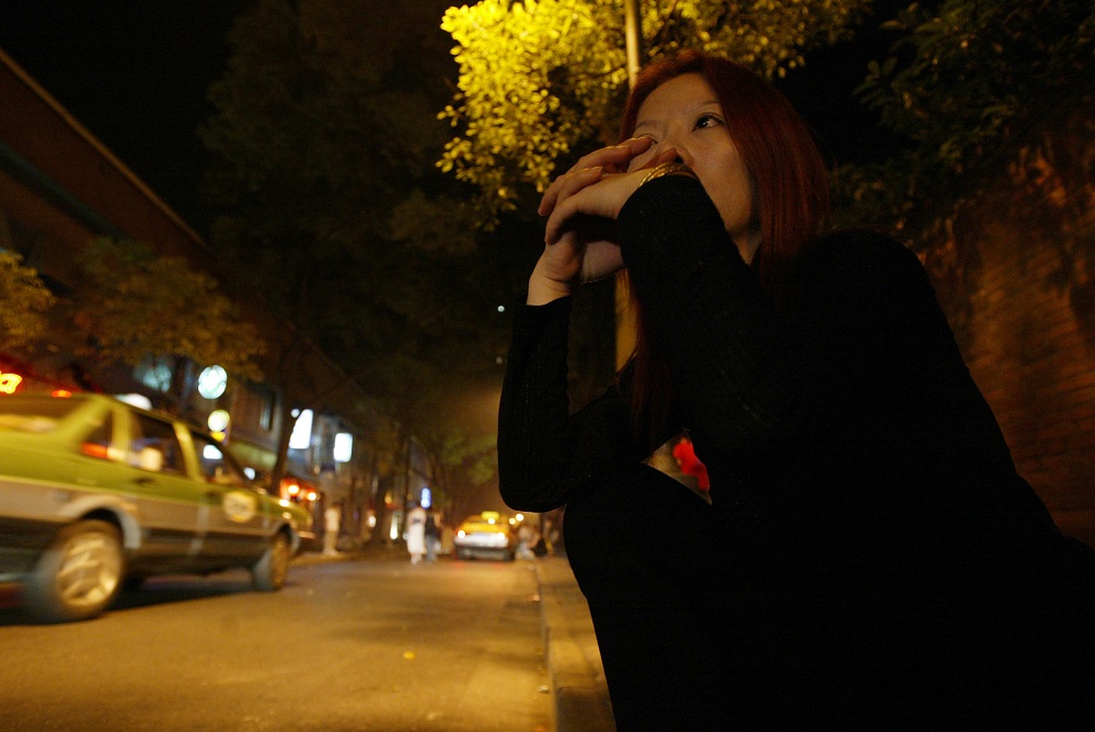 A prostitute sits in the dark as she waits for customers near a bar district in Shanghai June 7, 2003. u00e2u20acu201d Reuters pic   