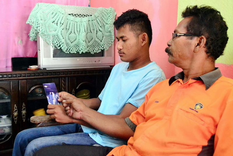 Mohamad Lazim Jusoh and his youngest son Muhamad Azlimuslim look at a photo of Umi Azlim at their home in Pasir Puteh June 9, 2016. u00e2u20acu201d Bernama pic