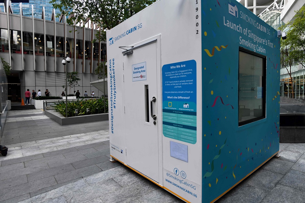 People linger near a smoking cabin, developed by Southern Globe Corporation, outside an office building in Singapore May 22, 2019. u00e2u20acu201d AFP pic          
