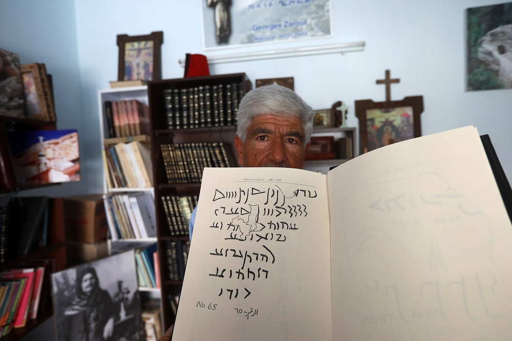 George Zaarour, a specialist in the Aramaic language, a notebook with Aramaic script written on it, in the Syrian mountain village of Maalula, in the Damascus region May 13, 2019. u00e2u20acu201d AFP pic  