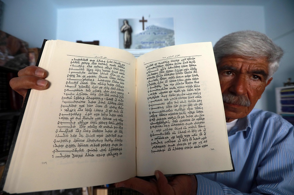 George Zaarour, a specialist in the Aramaic language, shows a book written in the Aramaic script in the Syrian mountain village of Maalula, in the Damascus region May 13, 2019. — AFP pic