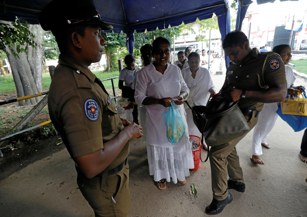 Police officers search the bags of the worshipers at an entrance of the Kelaniya Buddhist temple during Vesak Day, commemorating the birth, enlightenment and death of Buddha, in Colombo, Sri Lanka May 18, 2019. u00e2u20acu201d Reuters picnn