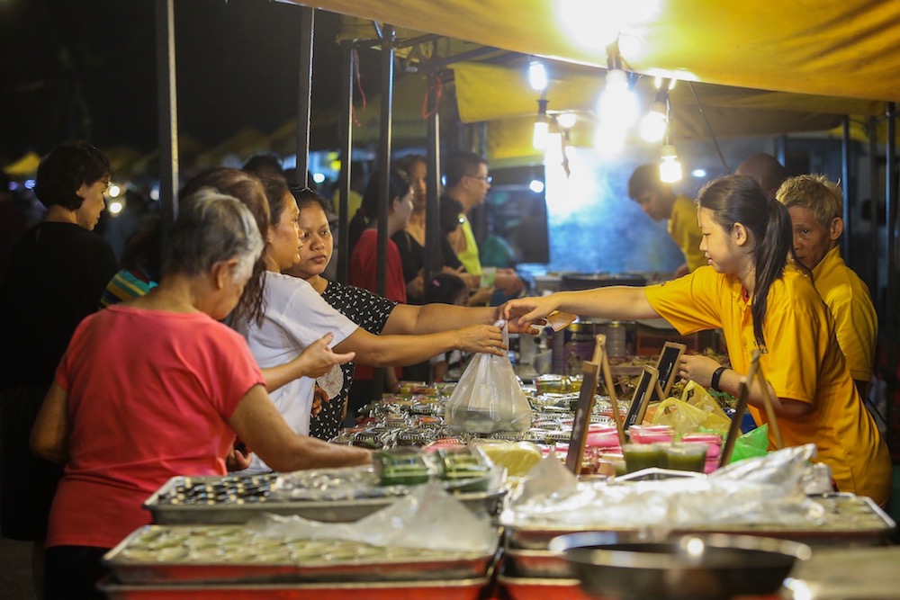 You can distinguish the hawkers at this ‘pasar malam’ by the yellow T-shirts they wear... the stalls also have standard canopies. — Picture by Hari Anggara