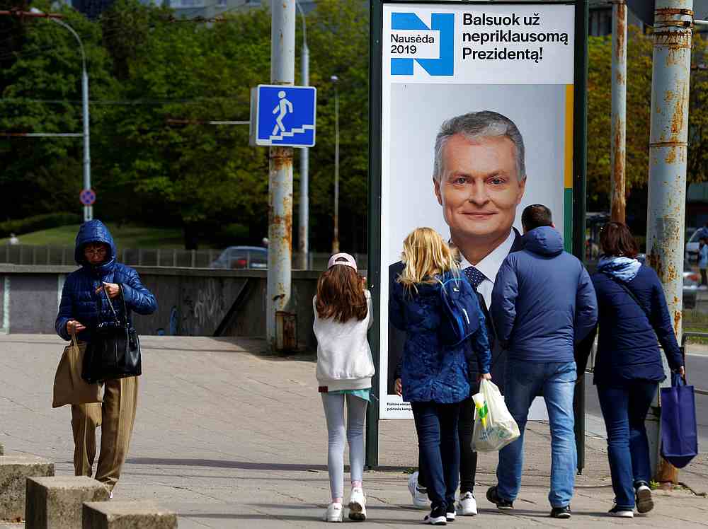 People walk past an election campaign placard of a Lithuanian presidential candidate Gitanas Nauseda in Vilnius, Lithuania May 9, 2019. u00e2u20acu201d Reuters pic