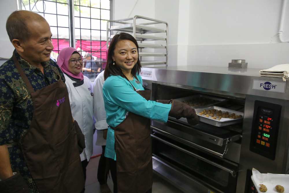 Hannah Yeoh puts a tray of cookies into the oven during the launch of the Women of Will's Community Kitchen in Kuala Lumpur May 25, 2019. u00e2u20acu2022 Picture by Yusof Mat Isa