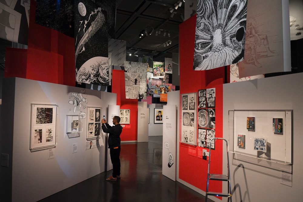 A visitor takes a photograph of a manga comic on display during a press preview for the exhibition ‘Manga’ at the British Museum in central London May 22, 2019. — AFP pic