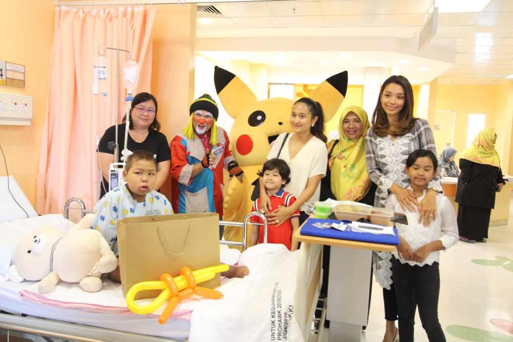 Nur Nadia SM Nasimuddin (in white) and Marion Caunter (right, in grey) distributing gifts to children at the Children’s Cancer Ward in Kuala Lumpur Hospital (HKL). — Picture courtesy of Naza Group