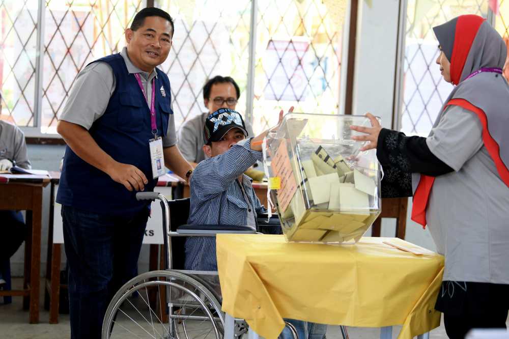 An EC personnel helps a disabled man to cast his ballot at a polling centre in Sandakan May 11, 2019. u00e2u20acu2022 Bernama pic