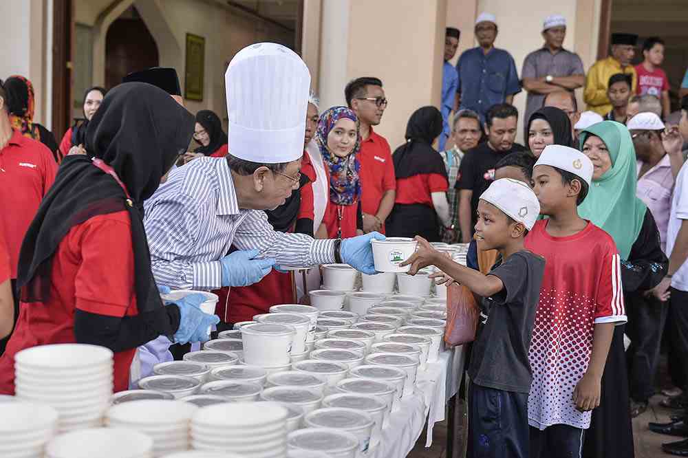 Sunway Group deputy chairman, Tan Sri Razman Hashim, handing out packets of u00e2u20acu02dcbubur lambuku00e2u20acu2122 to members of the community and mosque-goers during an event held at Masjid Al-Husna, Bandar Sunway, Petaling Jaya. u00e2u20acu2022 Picture by Miera Zulyana