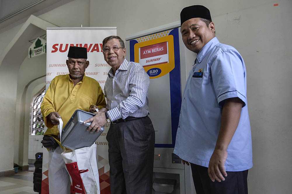 Sunway Group deputy chairman, Tan Sri Razman Hisham presenting, beneficiary Ismail Mohd Razali with his 2 kilogrammes of rice from the new rice ATM at Masjid Al-Husna, Bandar Sunway.