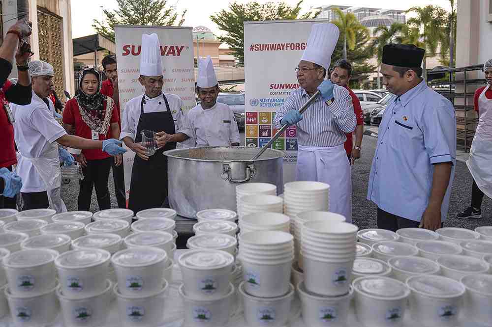 Razman helps the chefs from Sunway Resort Hotel & Spa to stir the large pot of ‘bubur lambuk’ before it was distributed to the community.