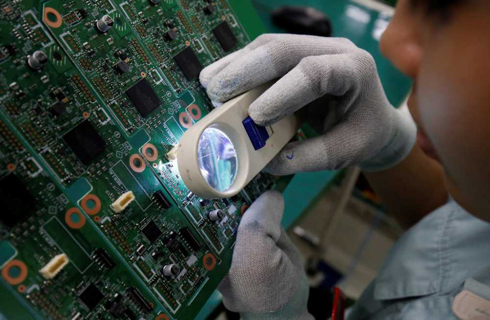 A woman looks through a magnifying glass to check errors on a printer circuit board at Manutronics Factory in Bac Ninh province, Vietnam. u00e2u20acu2022 TODAY pic via Reuters 