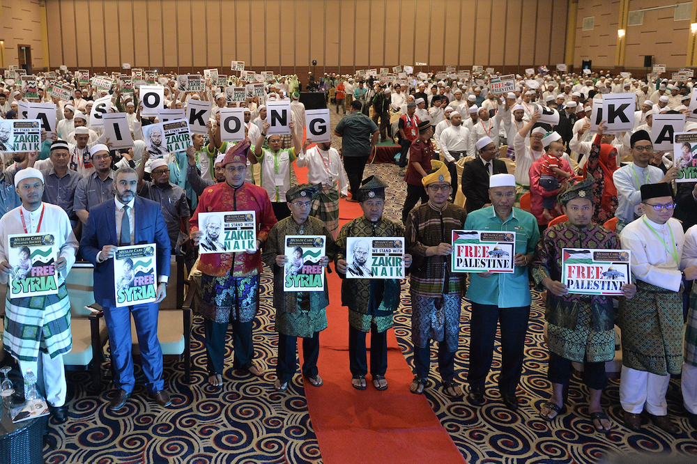 PAS members hold placards to show their support for Dr Zakir Naik and Mohamed Mursi during Muktamar 2019 in Gambang, Pahang June 19, 2019. u00e2u20acu201d Picture by Mukhriz Hazim