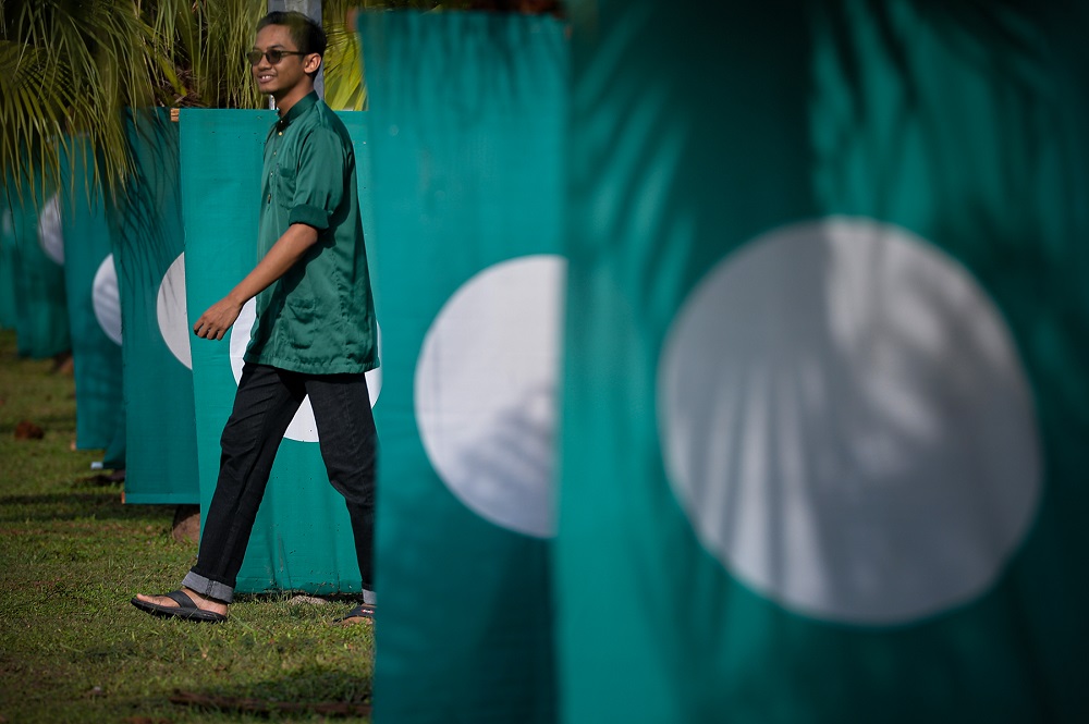 A PAS supporter walks near PAS flags at the 65th Muktamar in Kuantan June 22, 2019. u00e2u20acu201d Picture by Mukhriz Hazim