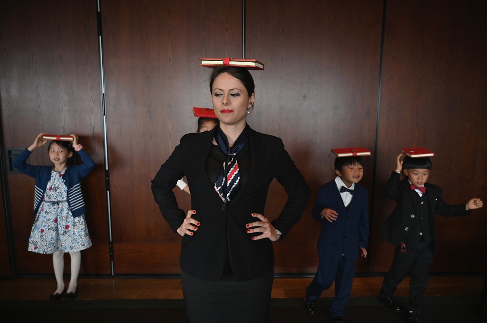 This picture taken on June 1, 2019, shows Danielle Liu (left) watching Miona Milakov walk with a book balanced on her head during an etiquette and manners class in central Shanghai. u00e2u20acu2022 AFP pic         