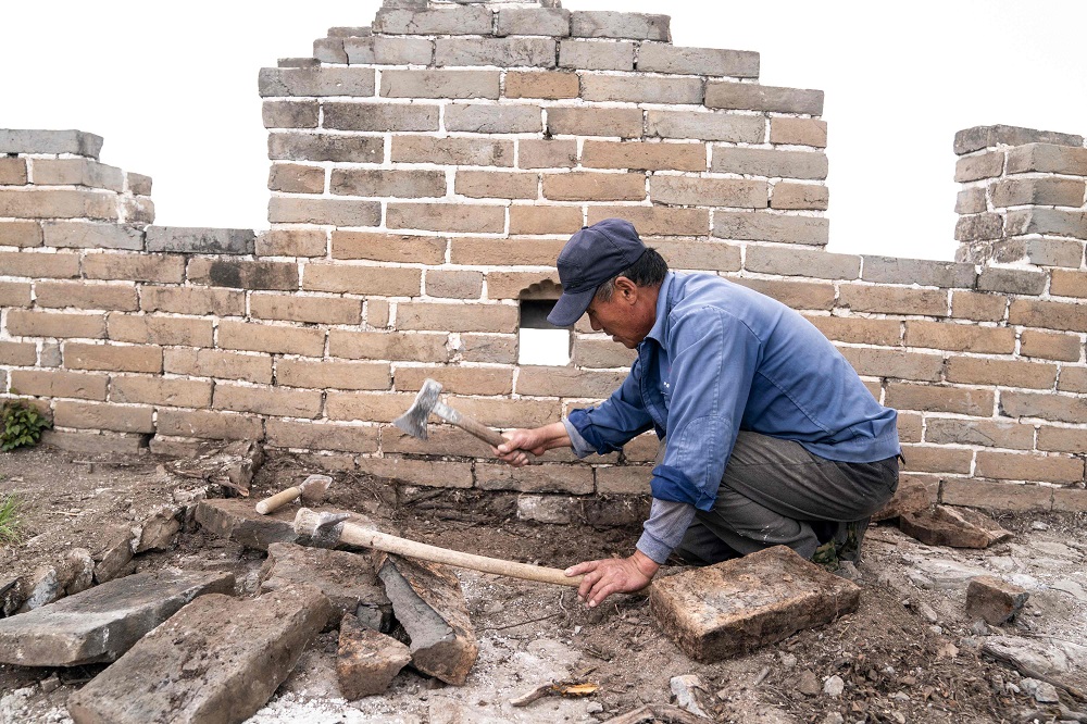 This picture taken on May 17, 2019 shows a worker removing roots at a restored part of the Great Wall in Xiangshuihu in Huairou District, on the outskirts of Beijing. ― AFP pic