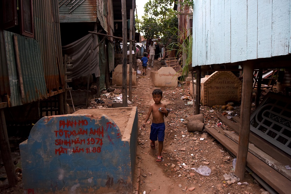 This picture taken on May 21, 2019 shows a boy walking past graves in Phnom Penh. u00e2u20acu201d AFP pic      