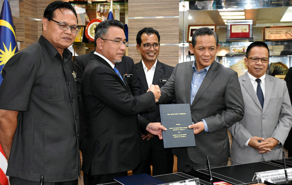 Adly Zahari and Datuk Seri Aminuddin Harun exchange documents after the signing of the MoU between Syarikat Air Melaka Berhad (SAMB) and Syarikat Air Negri Sembilan (Sains) in Melaka June 19, 2019. u00e2u20acu201d Bernama pic