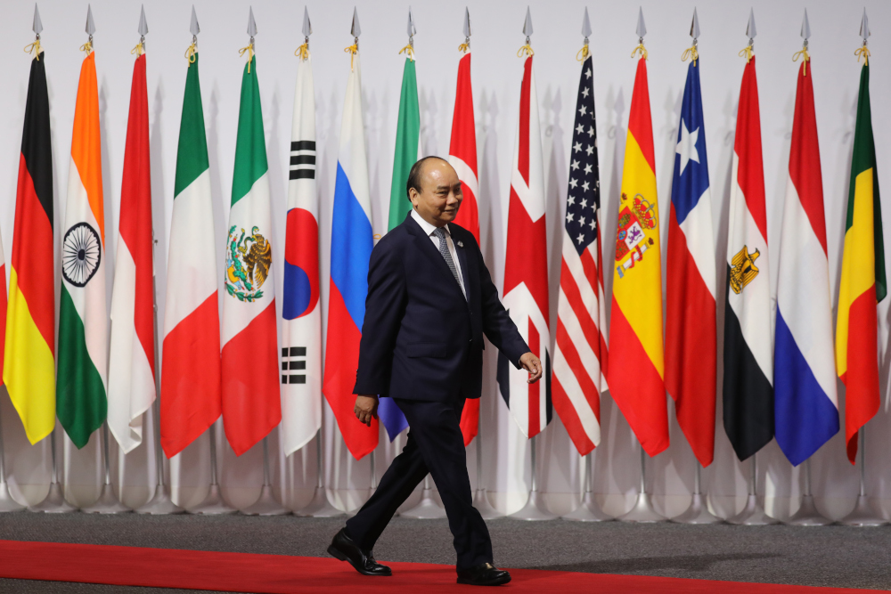 Vietnamu00e2u20acu2122s Prime Minister Nguyen Xuan Phuc walks past G20 member flags as he is welcomed by Japanese Prime Minister Shinzo Abe prior to the family photo at the G20 Osaka Summit in Osaka June 28, 2019. u00e2u20acu201d AFP pic