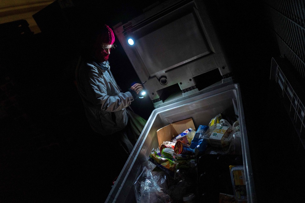 A dumpster diver picks through discarded food items in the back lot of a supermarket in Berlin May 17, 2019. u00e2u20acu201d AFP pic  