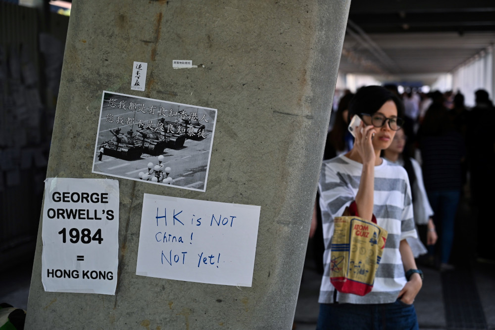 People walk past placards against a controversial extradition law proposal pasted on a wall near the Legislative Council Complex in Hong Kong June 14, 2019. u00e2u20acu201d AFP pic 