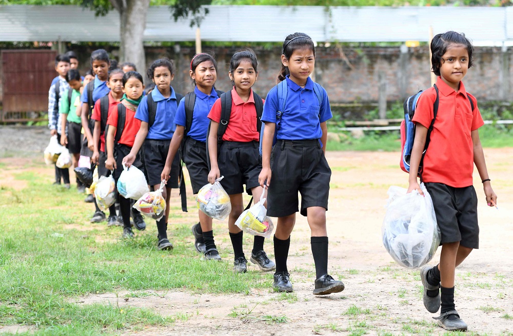 In this photo taken on May 20, 2019, Indian students walk in line holding plastic bags to submit them as school fees at the Akshar Forum school in Pamohi on the outskirts of Guwahati. u00e2u20acu201d AFP pic         