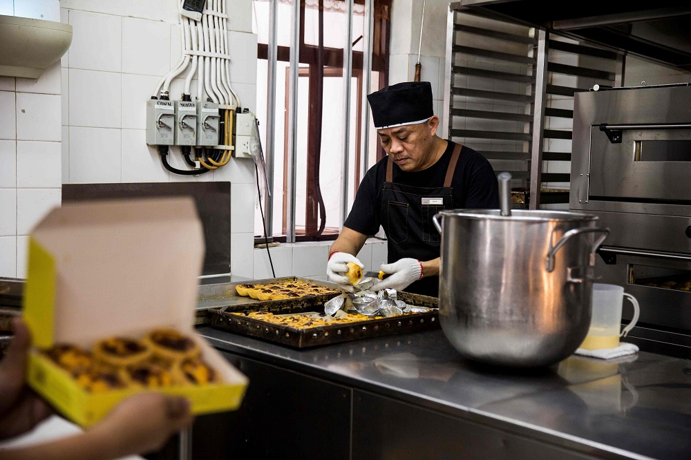 This picture taken on May 21, 2019 shows chef Dennis del Rosario preparing to box up cooked egg tarts at Lord Stow's bakery in Macau. — AFP pic 