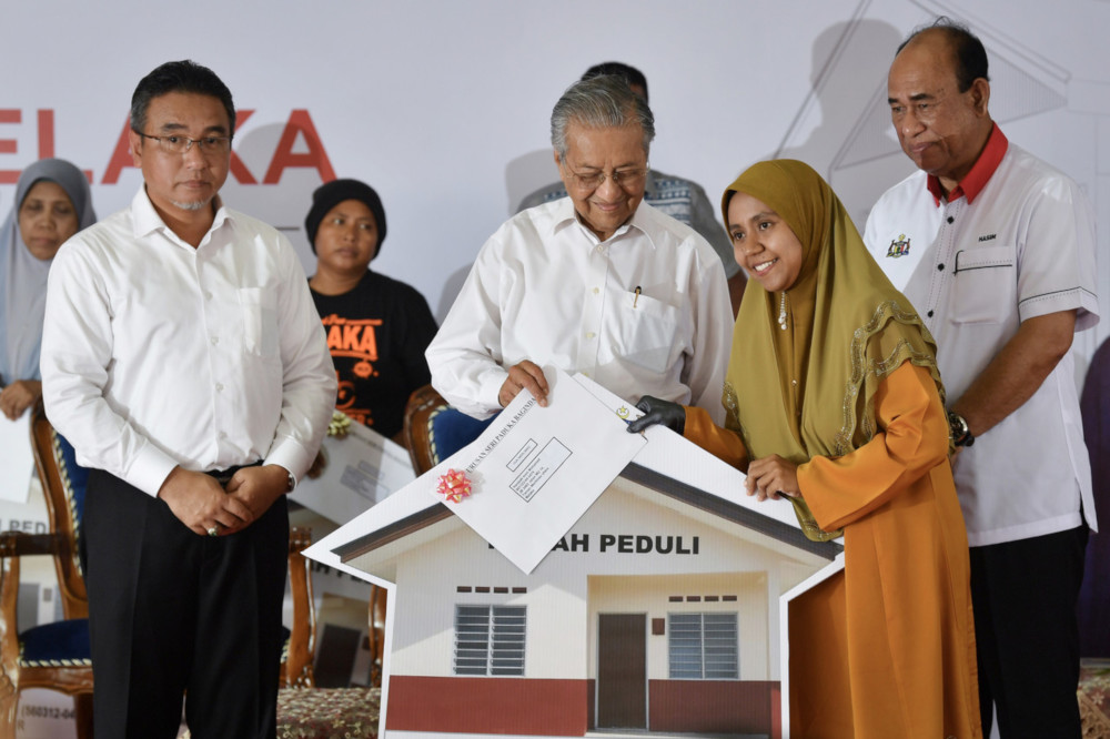Prime Minister Tun Dr Mahathir Mohamad hands over a replica of a house to owner Hanizah Mohamed (2nd right) during the launch of Melakau00e2u20acu2122s u00e2u20acu02dcRumah Peduliu00e2u20acu2122 June 10, 2019. u00e2u20acu201d Bernama pic 