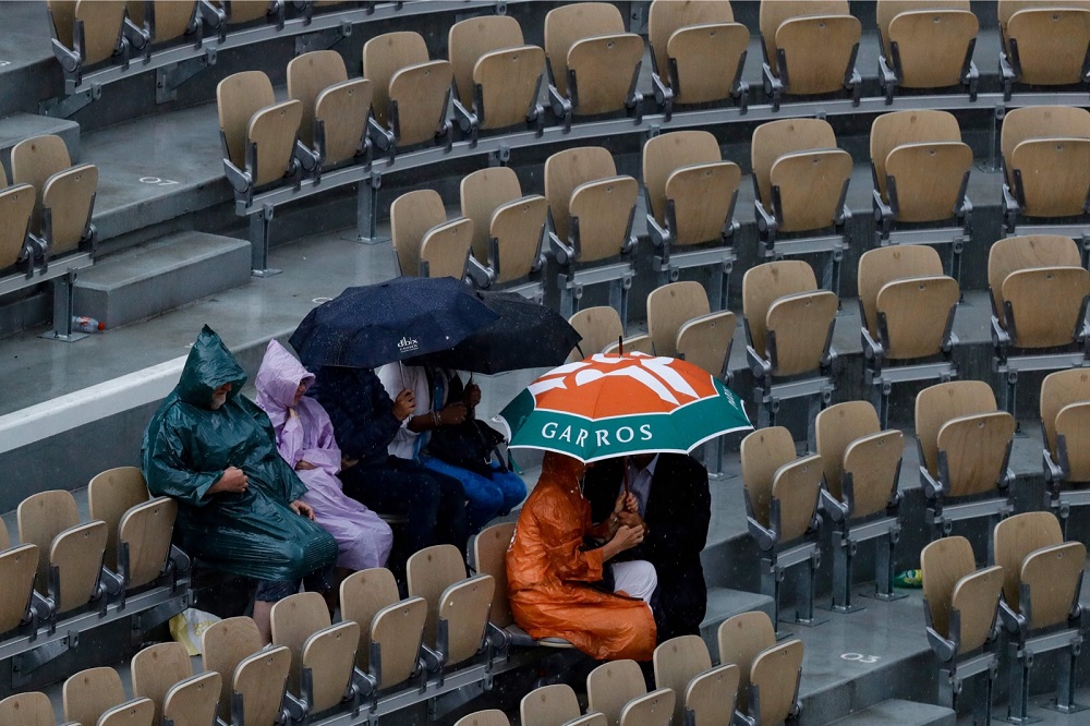 People sit under their umbrella as rain falls, during the men's singles quarter-final match between Spain's Rafael Nadal and Japan's Kei Nishikori in Paris June 4, 2019. u00e2u20acu201d AFP pic