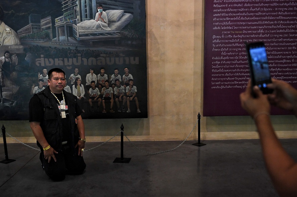 This picture taken on June 13, 2019 shows a visitor posing at a mural illustrating the rescue of the 12 boys from the u00e2u20acu02dcWild Boarsu00e2u20acu2122 football team after they were trapped in the Tham Luang cave, at the visitor centre in the Mae Sai. u00e2u20acu201d AFP pic     