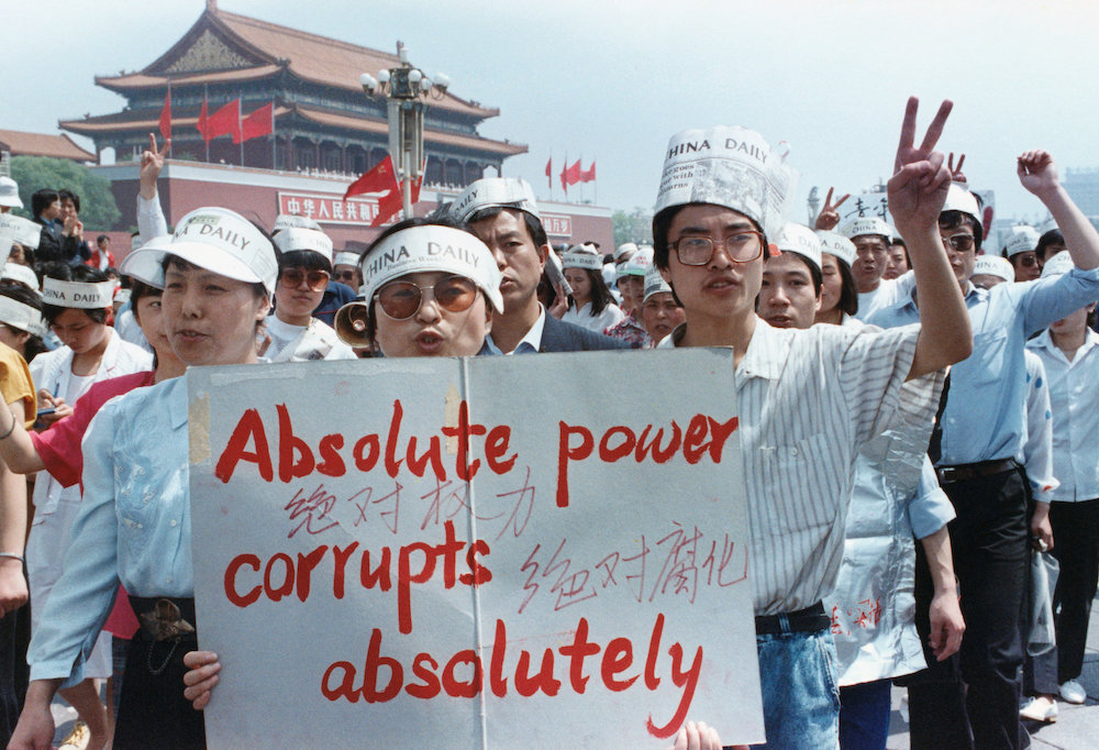 File photo of a demonstrator giving the victory sign as workmen finish putting a drape over a huge portrait of Chairman Mao in Tiananmen Square in Beijing, China, May 23, 1989. — Reuters pic
