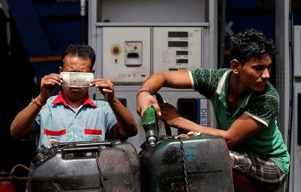 A worker checks a 500 Indian rupee note as a man fills diesel in containers at a fuel station in Kolkata  August 14, 2018. u00e2u20acu201d Reuters pic