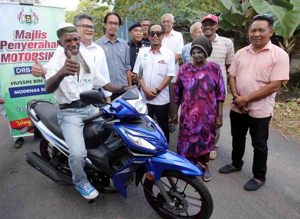 DRB-Hicomu00e2u20acu2122s Group Strategic Communications Head Mahmood Abdul Razak (second left) presents the motorcycle to Husin Kassim near his house in Taiping. u00e2u20acu2022 Picture by Farhan Najib