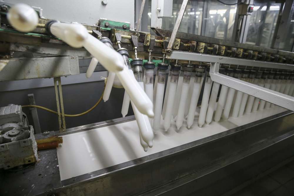 A long row of cleaned cylindrical glass formers are dipped in liquid latex and ammonia mix to get their first coating. ― Picture by Yusof Mat Isa