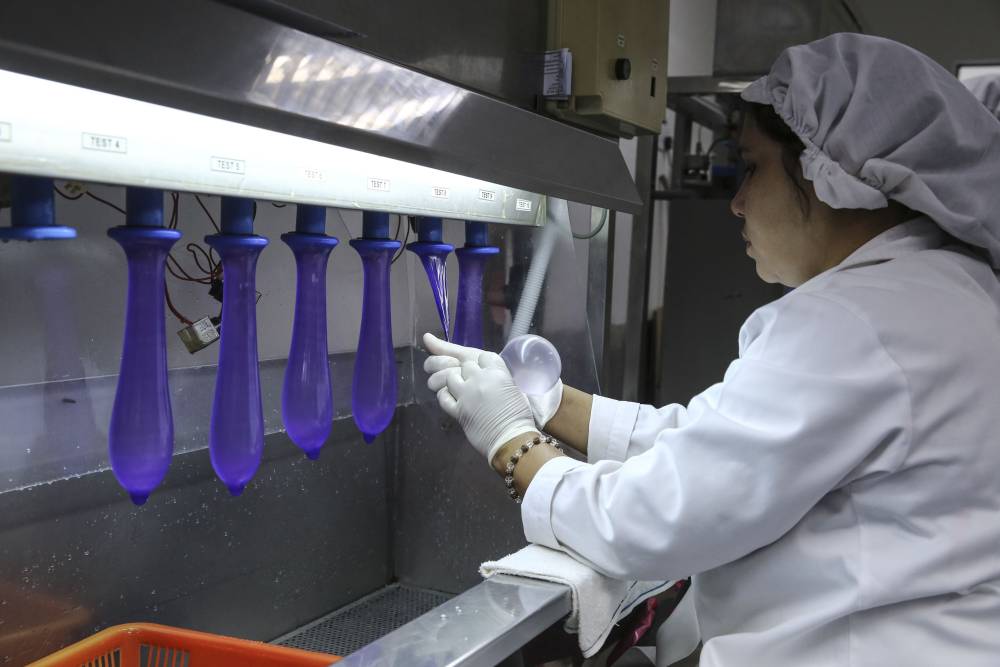 Staff inspect the condoms for signs of leaks by squeezing them around. ― Picture by Yusof Mat Isa