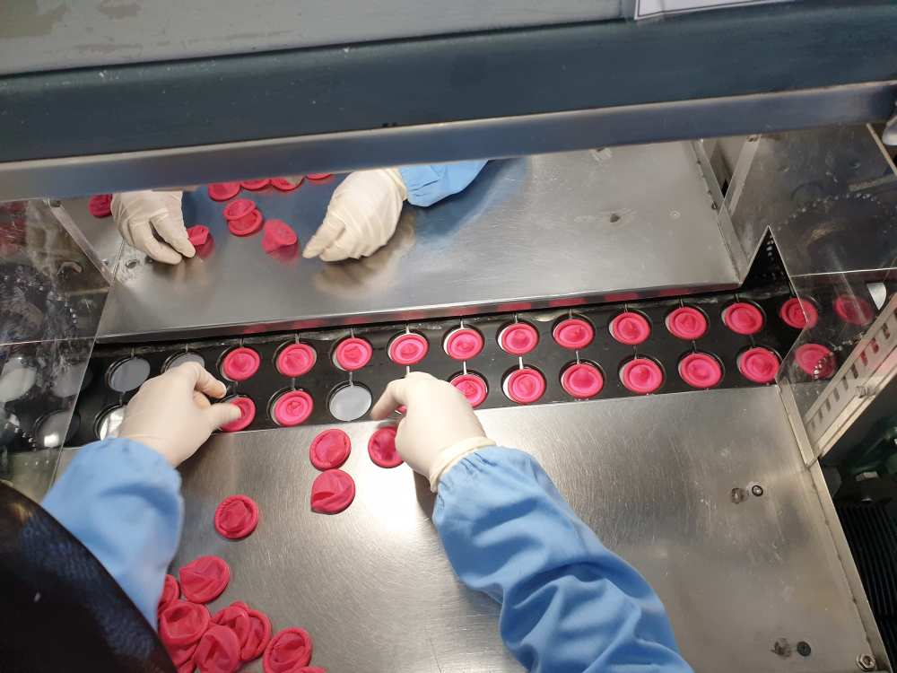 The rolled condoms are manually placed on a conveyer belt for packaging. ― Picture by Milad Hassandarvish  